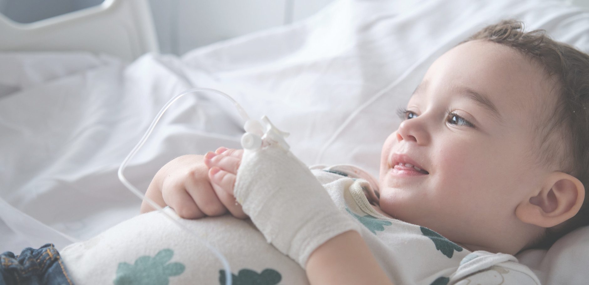 ninio_cama Niño sonriendo acostado con vía en la mano
